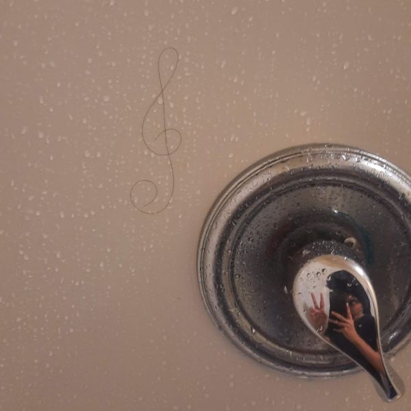 A strand of hair in the shape of a treble clef sign on a shower wall