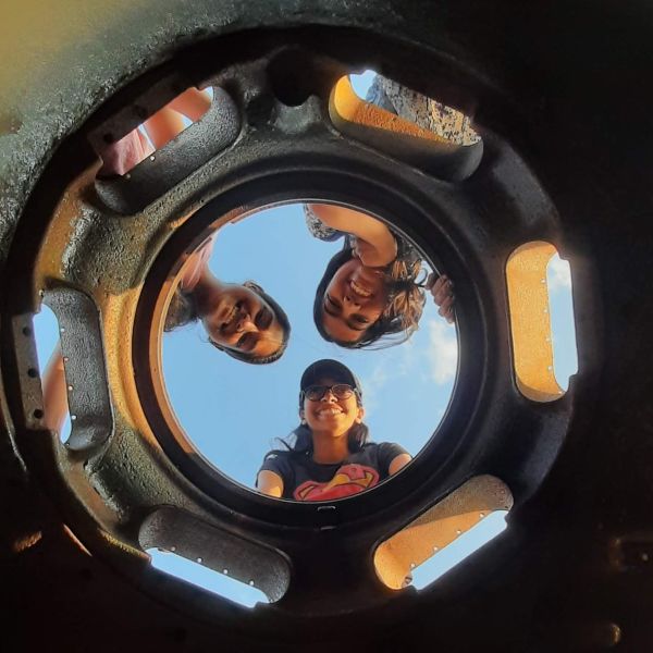 Three friends through a hole in an army tank